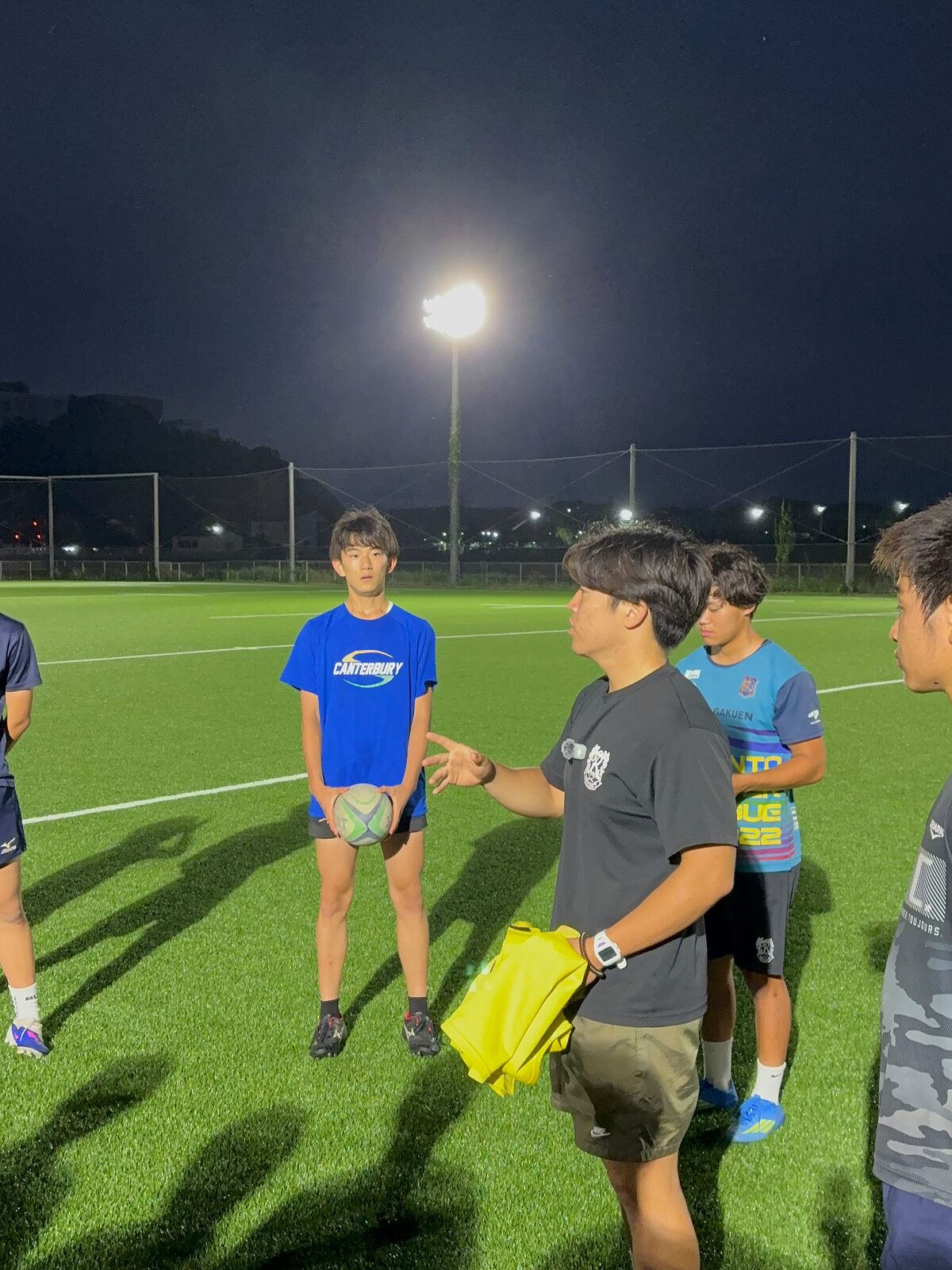 ナイター照明の下でコーチと話す選手たち